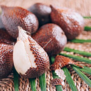 Red Salacca. Salak, snake fruits with palm leaves on rattan background. Copy space. Salacca zalacca
